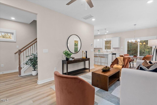 living room with light hardwood / wood-style flooring and ceiling fan with notable chandelier