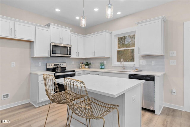 kitchen with white cabinets, appliances with stainless steel finishes, and hanging light fixtures