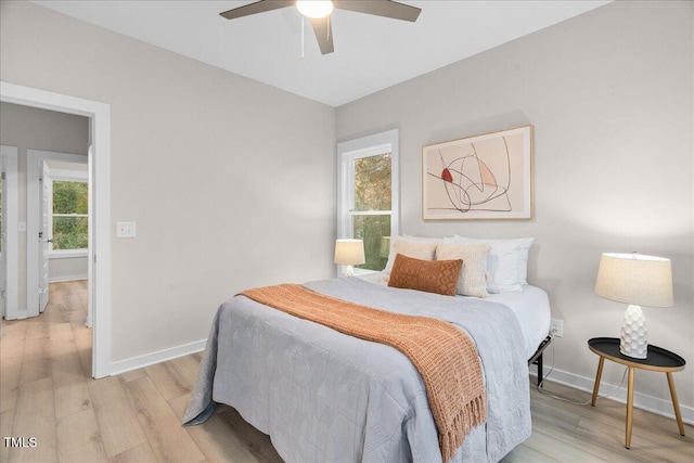 bedroom with ceiling fan, light hardwood / wood-style flooring, and multiple windows