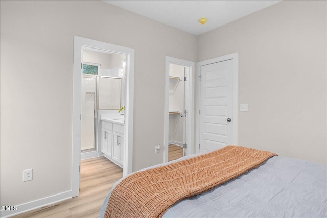 bedroom with ensuite bathroom, a walk in closet, light hardwood / wood-style flooring, and a closet