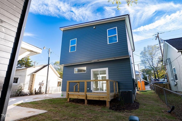 rear view of house featuring cooling unit, a yard, and a wooden deck