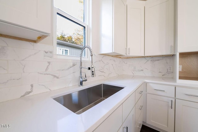 kitchen with tasteful backsplash, sink, and white cabinets