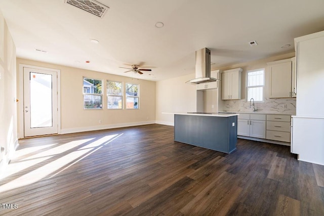 kitchen with island range hood, dark wood-type flooring, sink, white cabinets, and a kitchen island