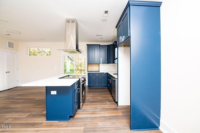 kitchen with blue cabinetry, a center island, stainless steel appliances, range hood, and light wood-type flooring