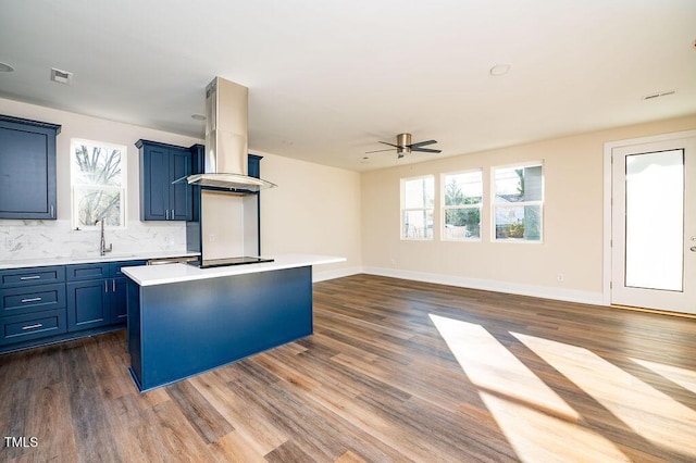 kitchen with ceiling fan, backsplash, black electric cooktop, island range hood, and a kitchen island