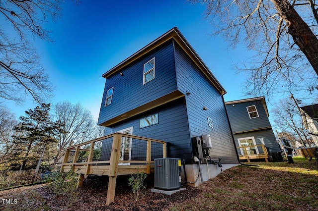 rear view of property with cooling unit and a deck