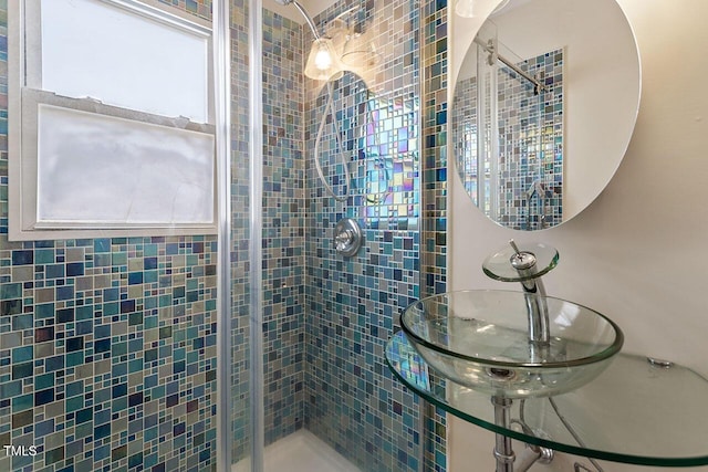 bathroom featuring a shower with door, a wealth of natural light, and sink