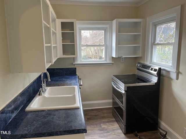 kitchen with dark wood-type flooring, range with two ovens, crown molding, white cabinetry, and sink