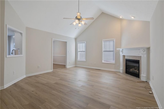 unfurnished living room with a tiled fireplace, ceiling fan, light hardwood / wood-style flooring, and vaulted ceiling