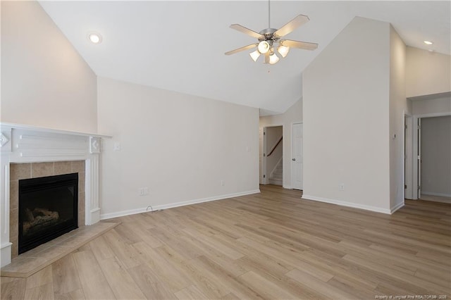 unfurnished living room with high vaulted ceiling, ceiling fan, light hardwood / wood-style floors, and a tile fireplace