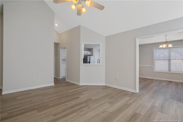 unfurnished living room featuring light wood-type flooring, ceiling fan with notable chandelier, and high vaulted ceiling