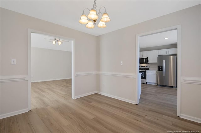 unfurnished dining area with ceiling fan with notable chandelier and light wood-type flooring