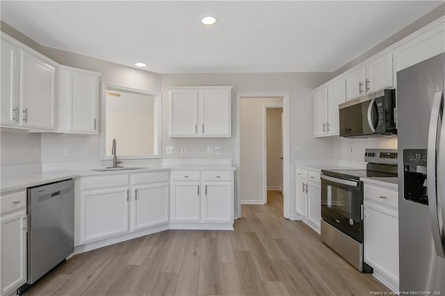 kitchen with white cabinets, light wood-type flooring, stainless steel appliances, and sink