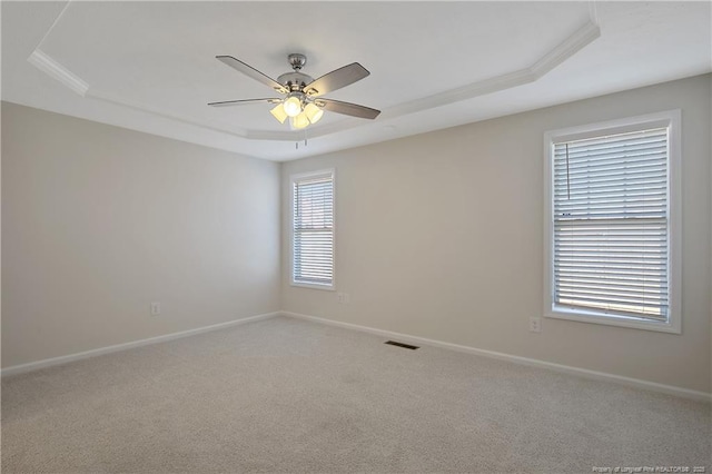 spare room featuring carpet flooring, a tray ceiling, and ceiling fan