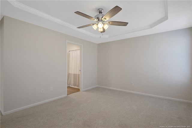 carpeted spare room featuring ceiling fan and a tray ceiling