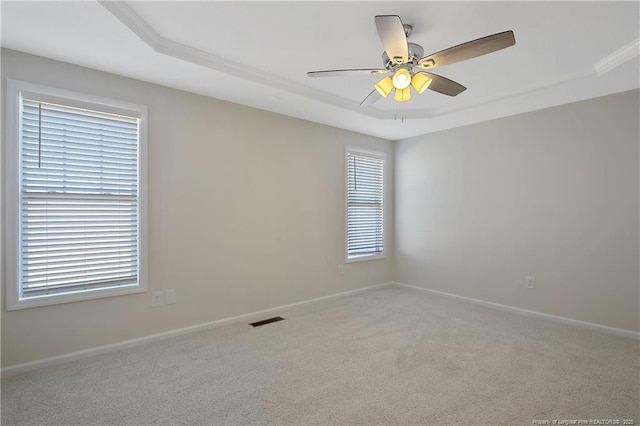 carpeted empty room featuring a tray ceiling, ceiling fan, and crown molding