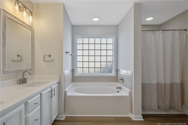 bathroom with vanity, hardwood / wood-style flooring, and a tub