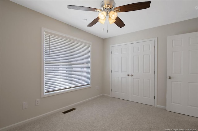 unfurnished bedroom with ceiling fan, a closet, and light carpet