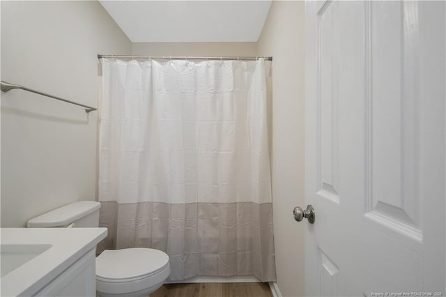 bathroom featuring vanity, lofted ceiling, toilet, walk in shower, and wood-type flooring