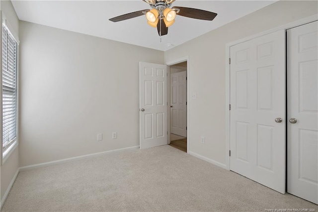 unfurnished bedroom with a closet, light colored carpet, and ceiling fan