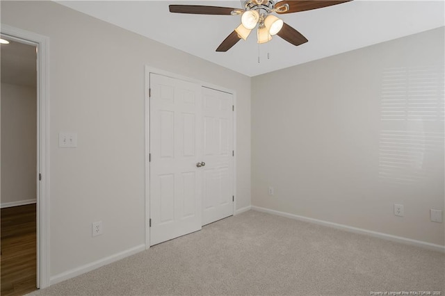 unfurnished bedroom featuring ceiling fan, light carpet, and a closet