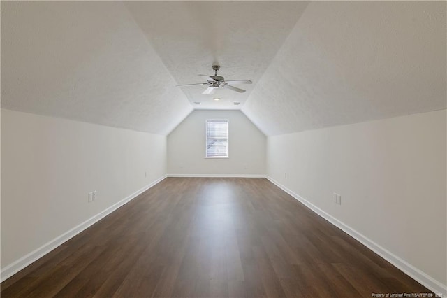 additional living space featuring a textured ceiling, lofted ceiling, ceiling fan, and dark wood-type flooring