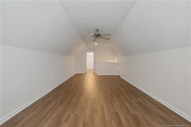 additional living space featuring ceiling fan, dark hardwood / wood-style flooring, a textured ceiling, and vaulted ceiling