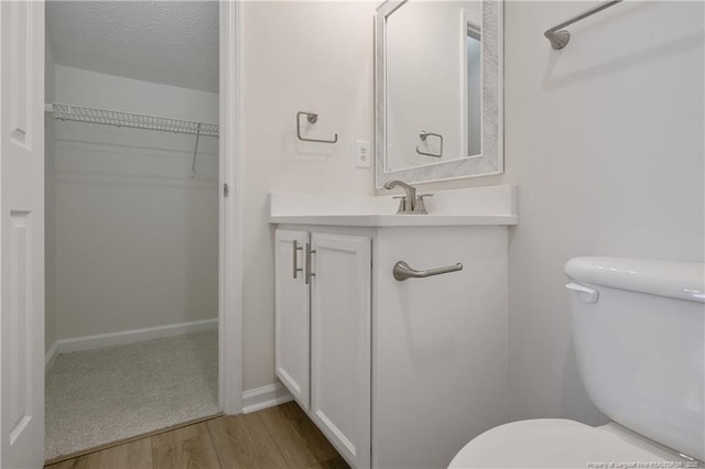 bathroom with toilet, vanity, a textured ceiling, and hardwood / wood-style flooring