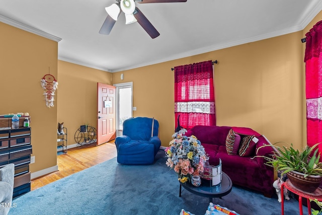 living area featuring baseboards, ceiling fan, wood finished floors, and crown molding