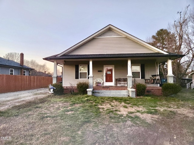 bungalow-style home featuring covered porch and fence