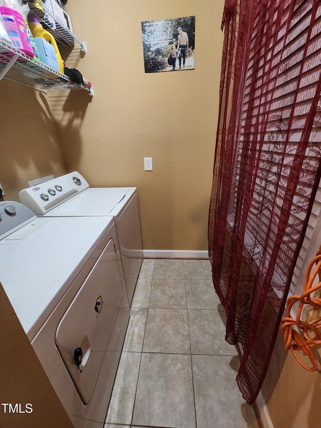 laundry area featuring laundry area, light tile patterned floors, baseboards, and washer and dryer