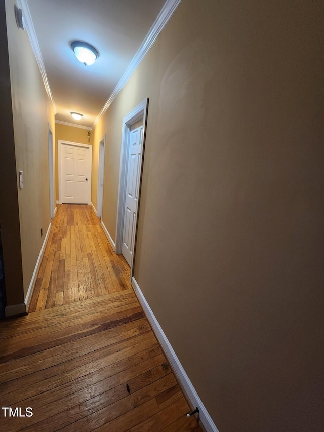 hall with ornamental molding, wood-type flooring, and baseboards