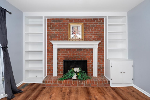 unfurnished living room with a brick fireplace and dark wood-type flooring