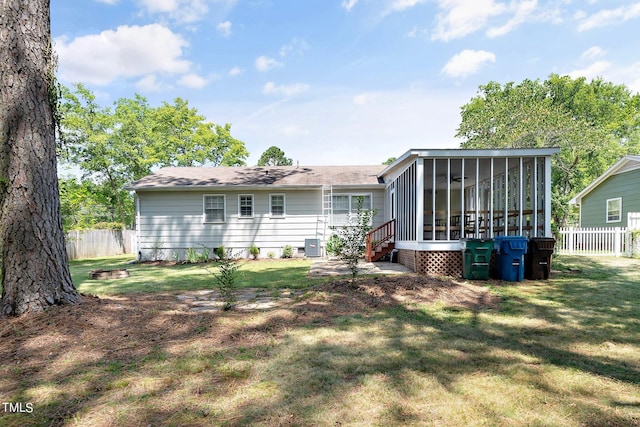 rear view of property featuring central air condition unit, a lawn, and a sunroom