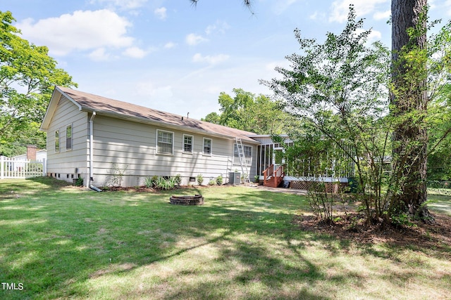 back of house featuring a lawn, cooling unit, and an outdoor fire pit