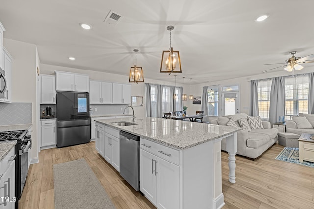 kitchen featuring appliances with stainless steel finishes, white cabinetry, backsplash, and sink