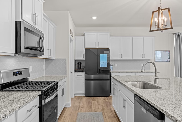 kitchen featuring light hardwood / wood-style floors, stainless steel appliances, pendant lighting, sink, and white cabinetry