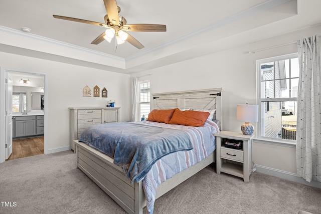 bedroom with ceiling fan, ensuite bathroom, a raised ceiling, and light carpet