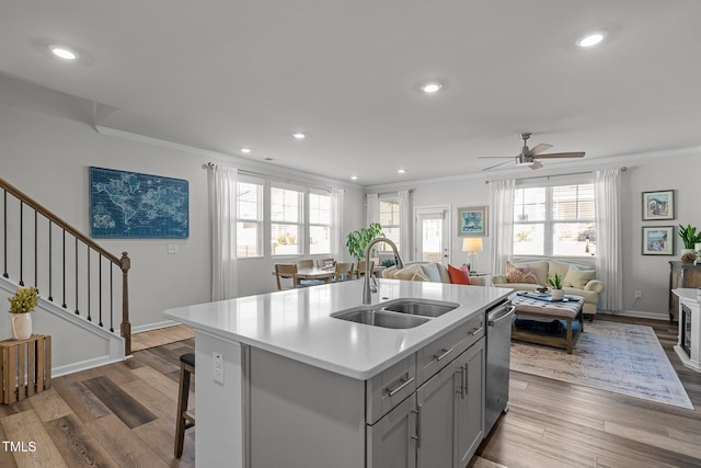 kitchen featuring ceiling fan, dishwasher, sink, gray cabinets, and a center island with sink