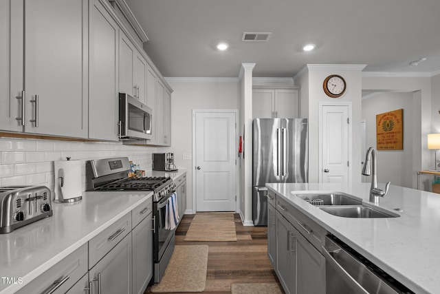 kitchen featuring gray cabinetry, sink, stainless steel appliances, dark wood-type flooring, and decorative backsplash