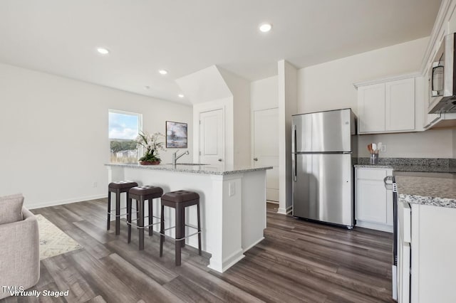 kitchen with dark wood-type flooring, stainless steel appliances, white cabinets, and a kitchen island with sink