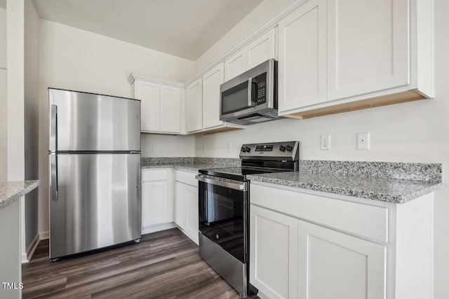 kitchen featuring dark wood-type flooring, appliances with stainless steel finishes, white cabinets, and light stone counters