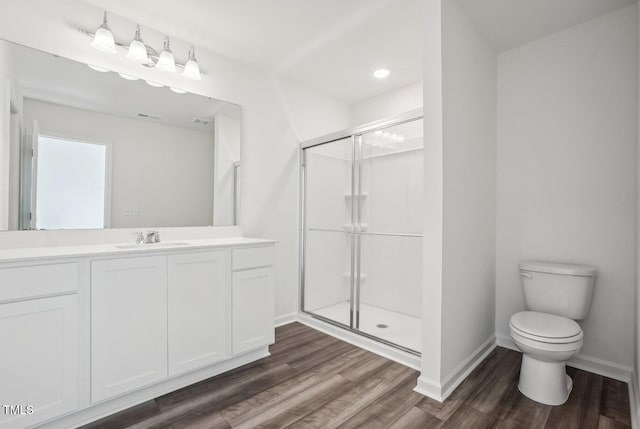 bathroom featuring toilet, hardwood / wood-style floors, a shower with door, and vanity