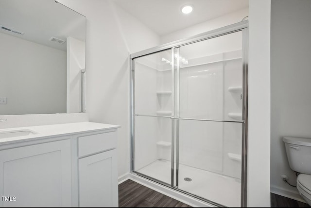 bathroom featuring toilet, vanity, an enclosed shower, and hardwood / wood-style floors