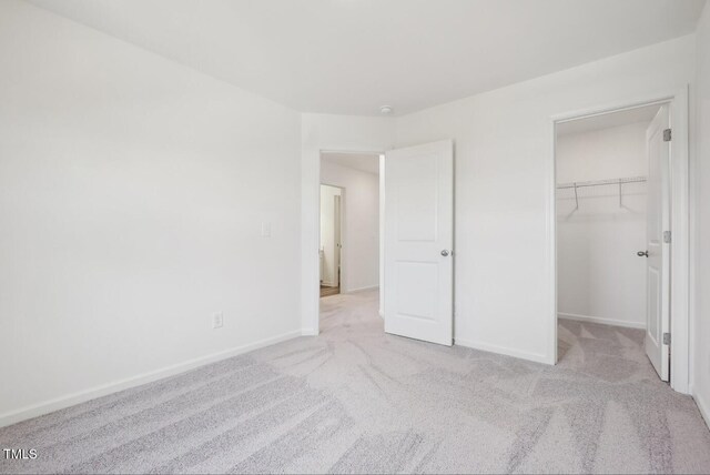 unfurnished bedroom featuring light colored carpet, a closet, and a walk in closet