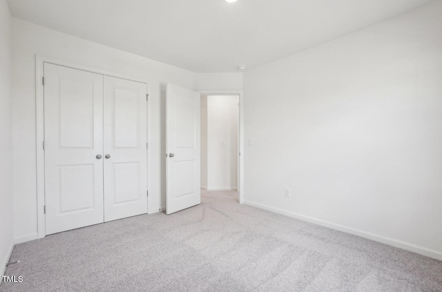 unfurnished bedroom with a closet and light carpet