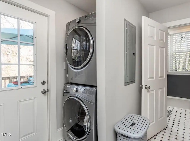 clothes washing area featuring stacked washing maching and dryer and a healthy amount of sunlight