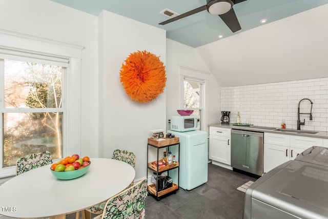 kitchen featuring lofted ceiling, backsplash, sink, stainless steel dishwasher, and white cabinetry