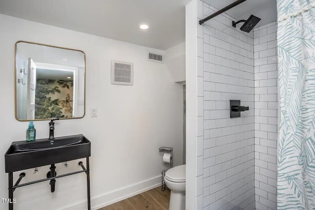 bathroom featuring toilet, sink, hardwood / wood-style floors, and walk in shower