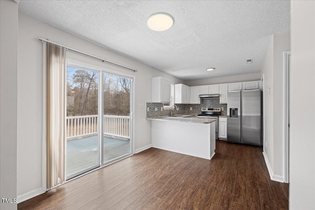 kitchen featuring white cabinetry, stainless steel appliances, kitchen peninsula, a textured ceiling, and decorative backsplash